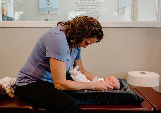 Dr. Pamela Stone providing child chiropracitc and giving an adjustment a newborn baby